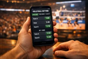 Mano che tiene uno smartphone con una schermata di quote sportive durante una partita di pallavolo