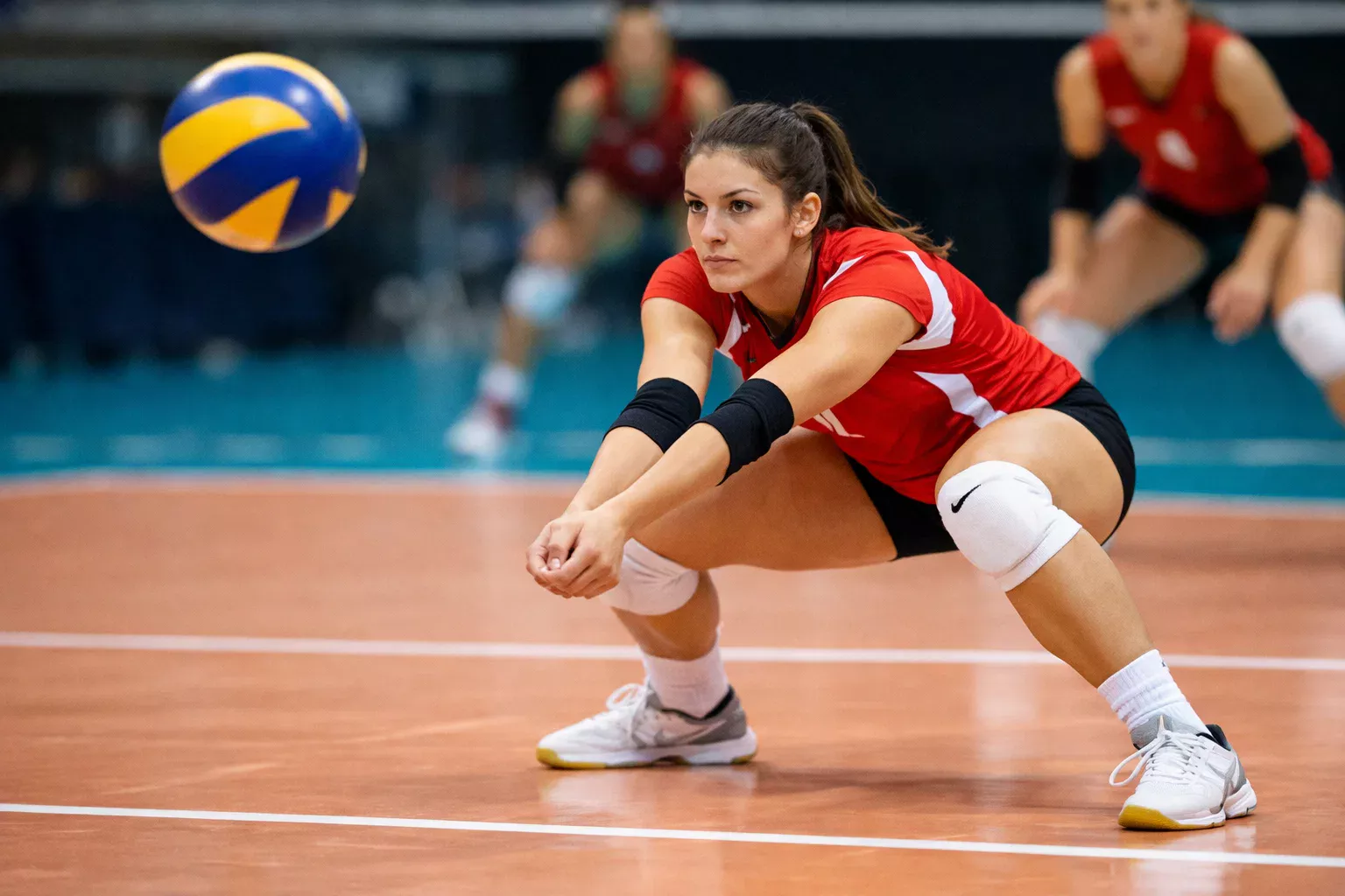 Giocatrice di pallavolo in posizione di ricezione pronta a ricevere un servizio